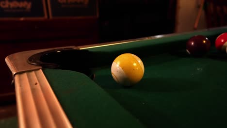 Yellow-ball-with-stripe-up-close-on-green-felt-table