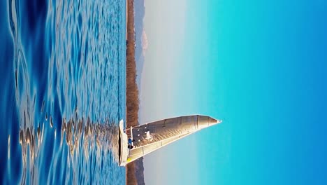 Low-angle-sea-level-view-of-small-yacht-boat-sailing-in-calm-open-waters-of-Maggiore-lake