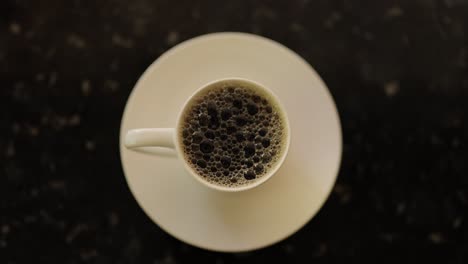 Kaffeeblasen-Knallen-In-Einer-Tasse-Auf-Einem-Teller-Auf-Einer-Marmorplatte