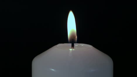 Close-up,-white-candle-flame-burning-against-black-background
