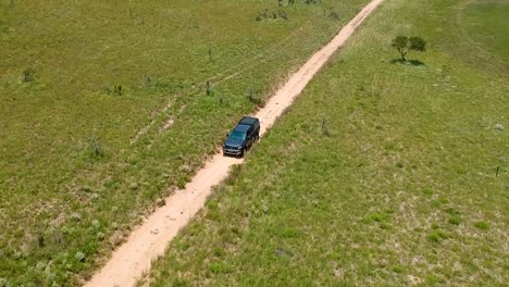 Vehicle-driving-on-a-dirt-road,-front-on-drone-tracking-shot