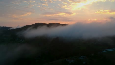 Sonnenuntergang-über-Einem-Berggipfel-Mit-Wolken,-Die-Davor-Hängen