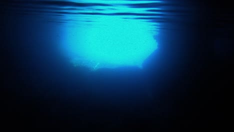 Underwater-view-of-the-entrance-of-a-sea-cave-withe-the-flashy-blue-light-reflecting-under-the-waving-surface,-Vis-island,-Adriatic-Sea,-Croatia