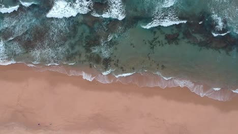 Hohe-Rotierende-Aufnahme-Von-Wunderschönem-Blauem-Ozeanwasser-Und-Unberührtem-Strand