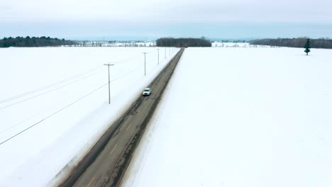 Drone-Volando-Por-Una-Carretera-Rural-Cruzando-Un-Solo-Coche-En-Invierno