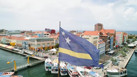 60-Fps-Erfassen-Eine-Luftaufnahme-Der-Curaçao-Flagge-In-Der-Innenstadt-Von-Willemstad