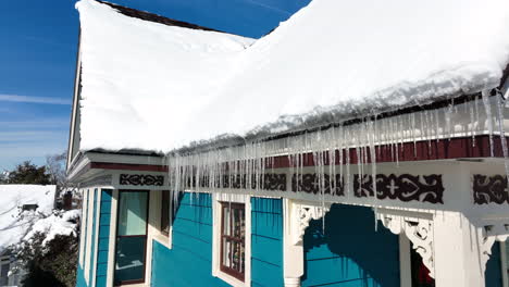 Icicles-on-roofline-covered-in-winter-snow