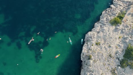 Vista-Aérea-De-Personas-Nadando-En-Kayak-Y-Surf-De-Remo-En-El-Adriático-Mediterráneo-De-Croacia