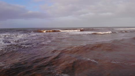 Fliegen-über-Schäumende-Wellen,-Die-Bei-Katwijk-Aan-Zee-In-Den-Niederlanden-Ans-Ufer-Rollen