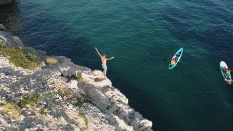 Aerial-view-of-a-person-cliff-jumping-into-the-Adriatic-Sea-in-Croatia-on-Krk-island