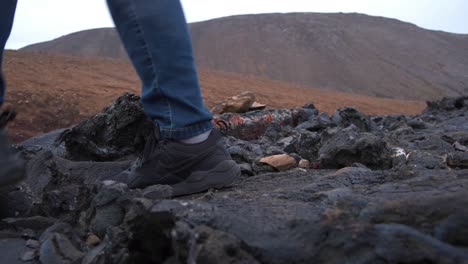 Close-up-of-hiker's-shoes-walking-over-sharp-volcanic-rocks-in-Iceland