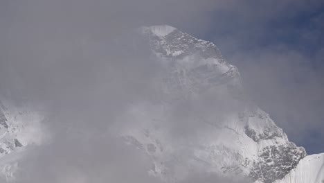 Timelapse-of-clouds-passing-a-huge-snowy-mountain,-clear-blue-sky,-beautiful-day