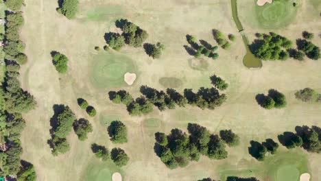 Drone-panning-wide-shot-of-golf-course-next-to-detached-villas-with-swimming-pool-in-Pilar,-Buenos-Aires