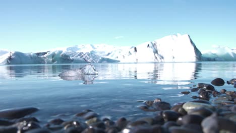 Black-pebbles-and-icebergs-on-the-sea-coast-of-Iceland,-close-up-shot