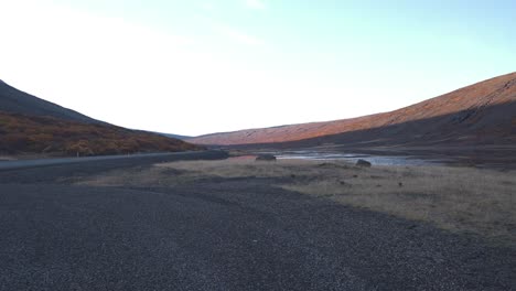 Asphalt-road-and-gravel-in-a-mountain-valley-in-Iceland-at-dusk