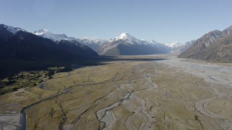 Aerial-shot-of-beautiful-mountains-above-a-valley-with-rivers-running-through-on-a-clear-day