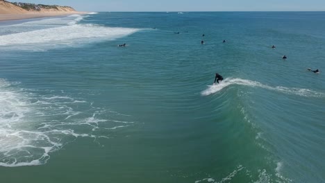 Surfer-Catches-Rides-Atlantic-Ocean-Wave-Group-of-Surfers-Cape-Cod-Sand-Dunes