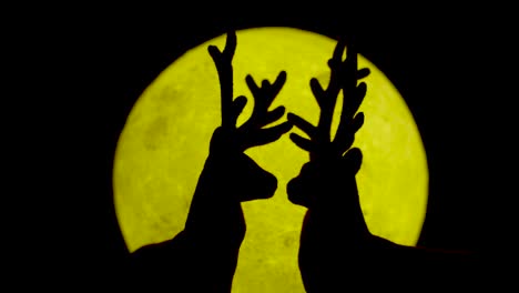 Silhouette-of-the-reindeer-connecting-at-the-yellow-moon-at-night