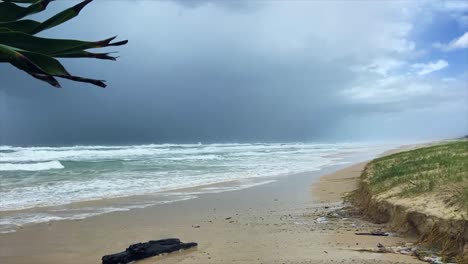 Storm-clouds-approach-and-a-fierce-wind-whips-up-over-North-Stradbroke-Island's-deserted-Main-Beach,-with-the-violent-foaming-surf-pounding-the-desolate-coastline