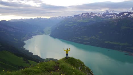 Elated-man-in-yellow-jacket-loves-panoramic-view-from-mountain-lookout