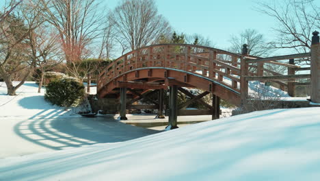Slow-pan-left-shot-of-quiet-snow-covered-bridge-on-sunny-day