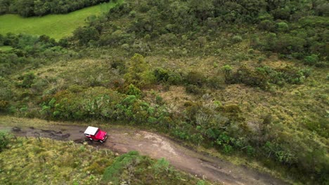 Aerial-circular-shot-of-a-jeep-crossing-a-countryside-road-at-Cundinamarca,-Colombia