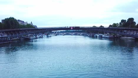Low-drone-shot-above-Seine-River-passing-under-a-bridge,-towards-Grand-Palais,-Concorde