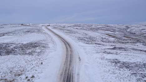 North-York-Moors,-road-near-to-the-Lion-Inn-Blakey-Ridge-covered-in-heavy-snowfall-difficult-driving-conditions-in-winter-snow---aerial-footage-dji-inspire-2