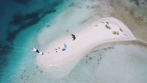 TOP-DOWN-Atoll-with-two-Kitesurfers-on-white-sand-beach-to-kitesurf-in-azure,-Los-Roques
