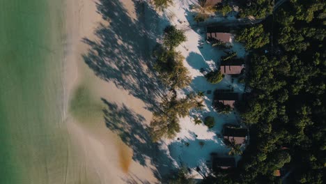 Beautiful-luxury-tourist-resort-right-on-the-white-sandy-beach-with-green-palm-trees-with-huge-shadows-and-in-the-clear-Gulf-of-Thailand