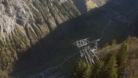 Vista-De-Drones-Sobre-El-Teleférico-Suizo-En-Verano-Caída-Vertical-Descendente-Al-Pueblo-De-Lauterbrunnen-En-El-Valle-De-La-Montaña