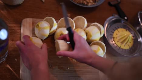 Stationary-shot-of-a-woman's-hands-while-slicing-peeled-lemons-in-half-to-prepare-them-for-juice-extraction