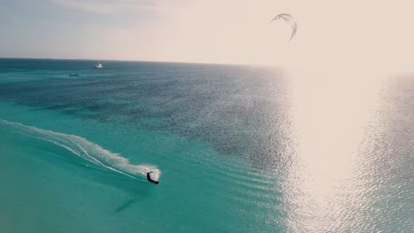 Man-kitesurf-backlit-at-sunset-on-turquoise-sea-water,-drone-shot-pan-right-Los-Roques