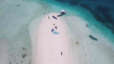 Top-view-atoll-reveal-people-kitesurf-enjoy-sunny-day-on-white-sand-beach-and-turquoise-sea-water