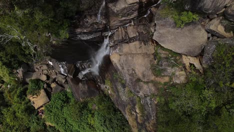 Nach-Einem-Langen-Spaziergang-über-Den-Rand-Des-Höheren-Liebhaberblattwasserfalls-Blicken-Mehrere-Touristen-Auf-Das-Wasser,-Das-über-Die-Geschnitzten-Felsen-Zwischen-Die-Natur-Von-Sri-lanka-Fällt
