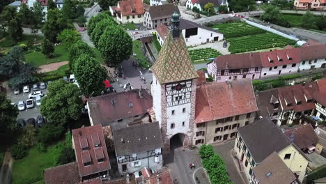 A-rearward-aerial-drone-footage-of-the-clock-tower-while-revealing-the-houses,-the-roads,-and-the-whole-village
