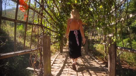 Hermosa-Mujer-Europea-Caucásica-Rubia-Caminando-Sobre-Un-Puente-De-Bambú-En-El-Pueblo-De-Montaña-Pai-En-Tailandia-En-Un-Cálido-Día-De-Verano