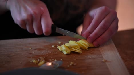 A-stationary-footage-of-a-woman's-hands-while-slicing-peeled-ginger-using-a-knife-on-top-of-the-counter