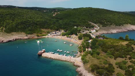 Aerial-view-of-packed-Risika-Beach-on-Krk-island-in-Croatia-with-a-pirate-ship-in-summertime