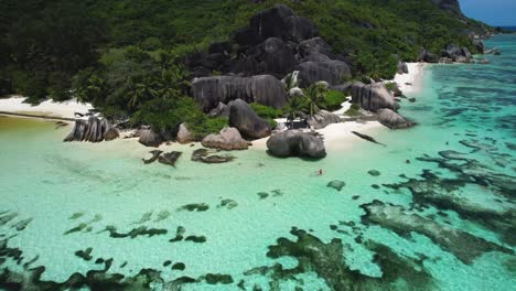 Vista-Aérea-De-Una-Mujer-En-Kayak-En-La-Playa-De-Seychelles-Con-Rocas-Y-Agua-Turquesa