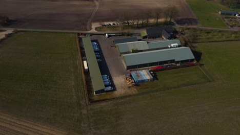 Amazing-scenery-of-a-farm-with-sheds-in-nature-surrounded-by-trees-and-fields-sunny-drone-shot