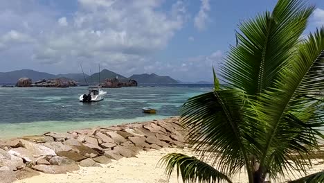 La-Digue-Seychellen-Tropischer-Strand-Mit-Boot-Angedockt-Wellenbrecher-Und-Palmen