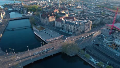 Striking-aerial-bird's-view-of-city-of-Zurich-at-golden-hour,-lowering-to-train-station,-Switzerland
