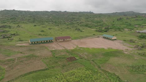 AERIAL---Village-school-and-school-yard,-Jos-Plateau,-Nigeria,-rising-reverse