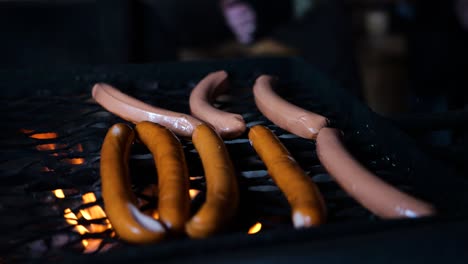 Camera-pulling-back-shot-of-fresh-delicious-sausages-on-a-barbecue-grill-over-a-fire