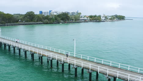 Sportlerläufer-Auf-Langem-Pier-über-Der-Wasserpromenade,-4k-Drohnenüberführung-Aus-Der-Luft