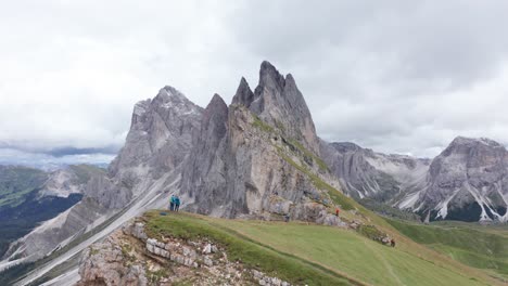 Hikers-at-scenic-Seceda-lookout---amazed-by-dramatic-Fermeda-Towers,-Dolomites
