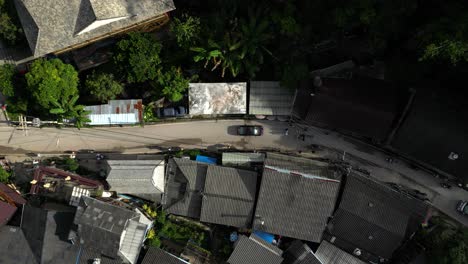 Slow-motion-aerial-road-flanked-by-old-wooden-houses-in-Thai-mountain-village