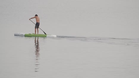 Young-fit-man-paddles-in-a-paddle-board-in-calm-sea-at-sunrise-in-slow-motion-60fps