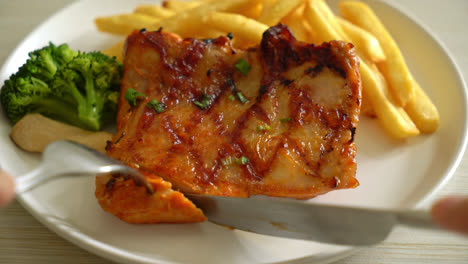 slicing-grilled-chicken-steak-with-potato-chips-or-french-fries